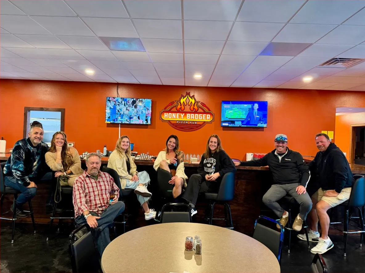 Guests at the bar under the Honey Badger sign