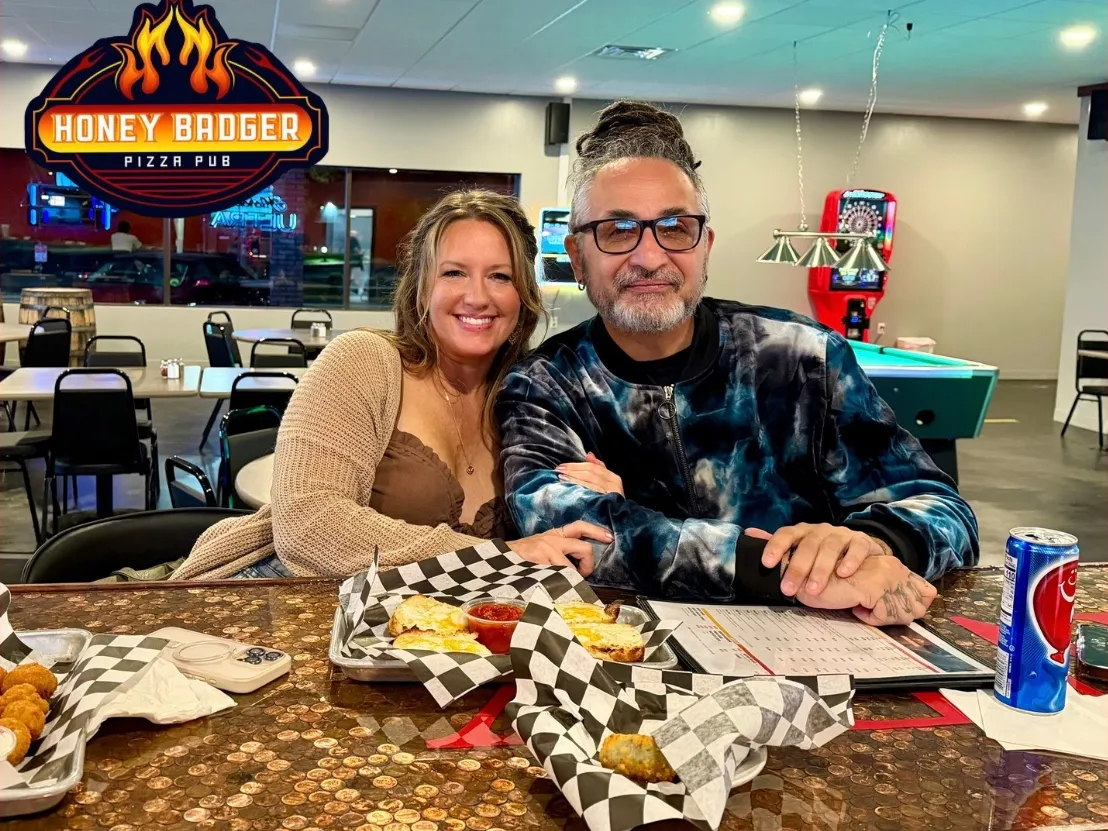 Two guests with wings and fries at the bar top