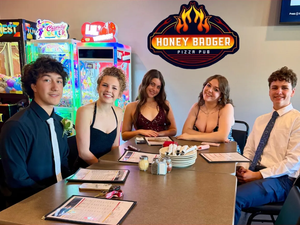 Five friends at a table by the arcade machines