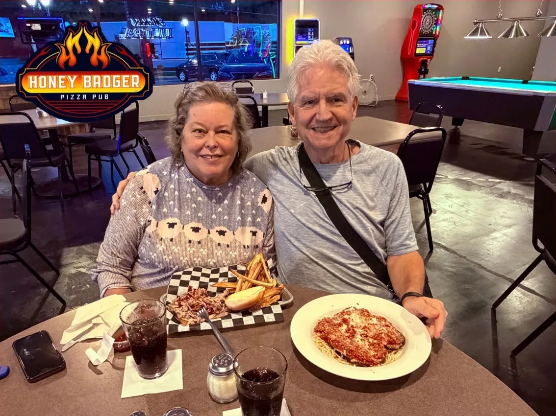 Two guests at a table with the pool table behind them